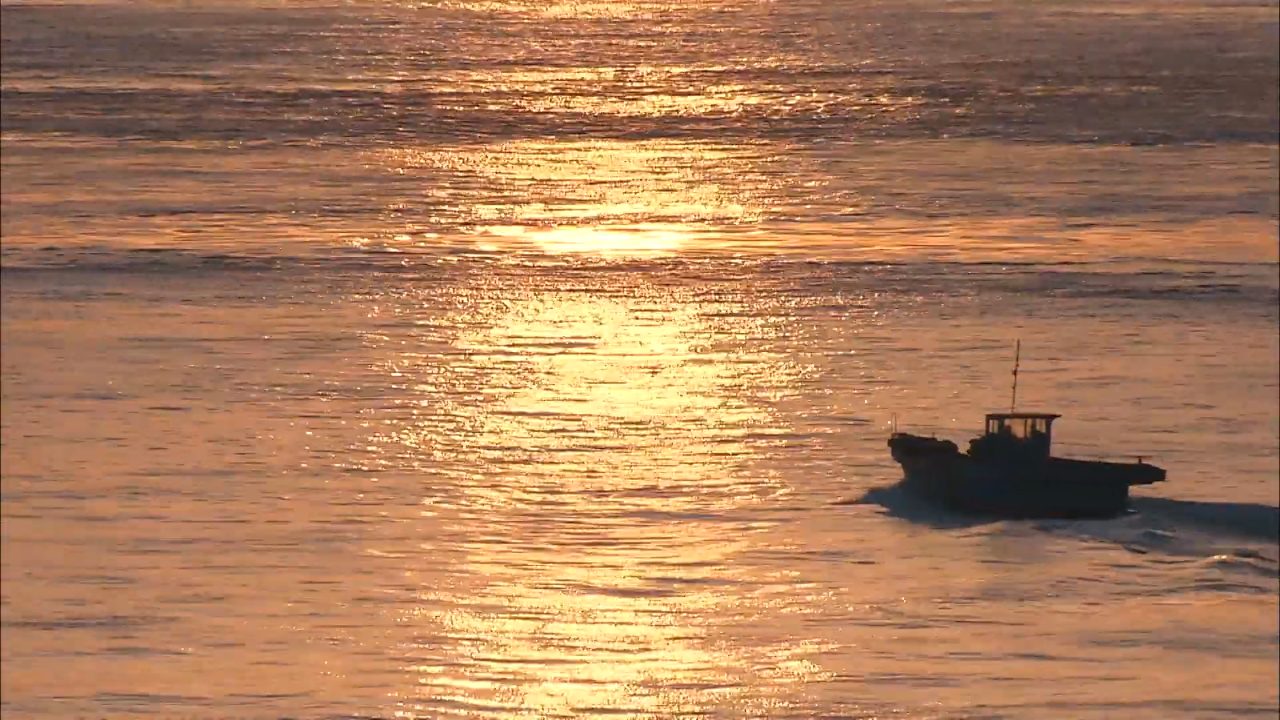 夕日に光る海をゆく小さな船
